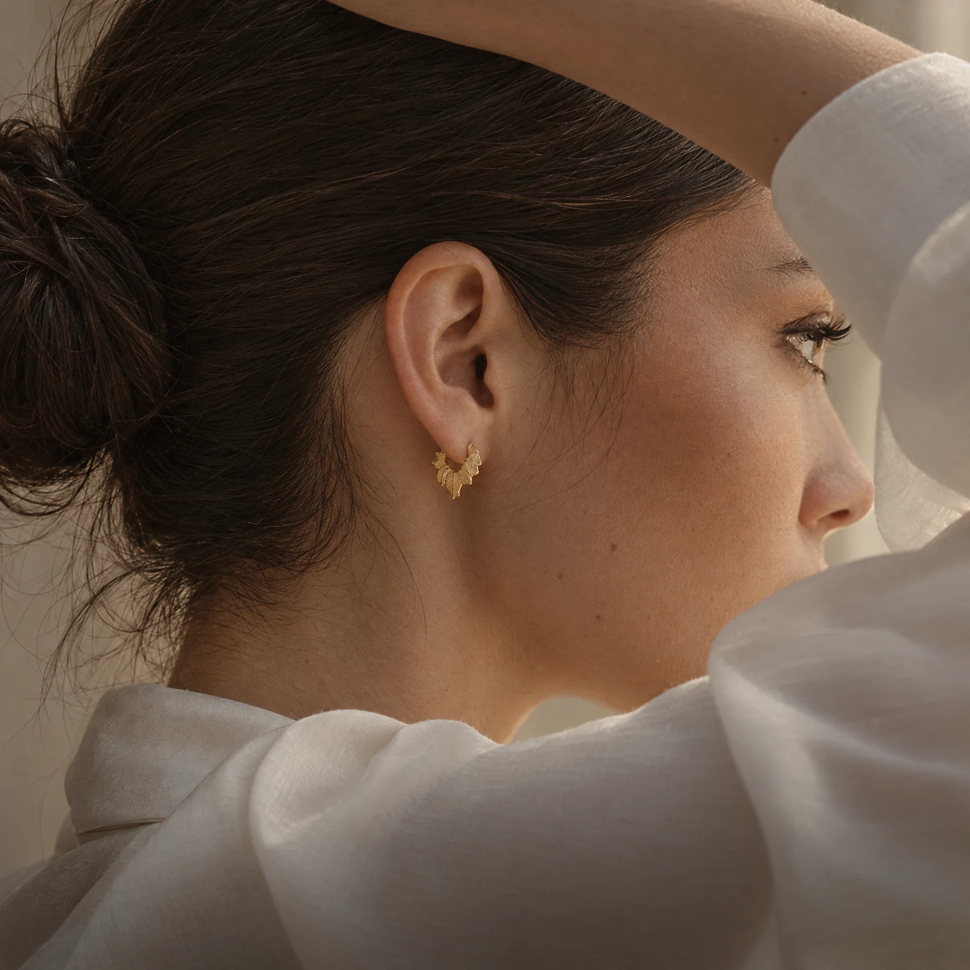 Gold leaf hoop earring with ivory silk and warm window light